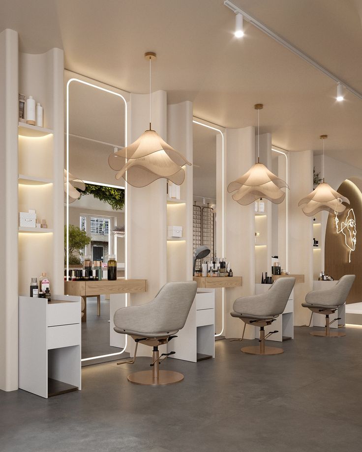 Bright salon interior with curved cream walls, backlit mirrors, petal-shaped pendant lamps and grey styling chairs